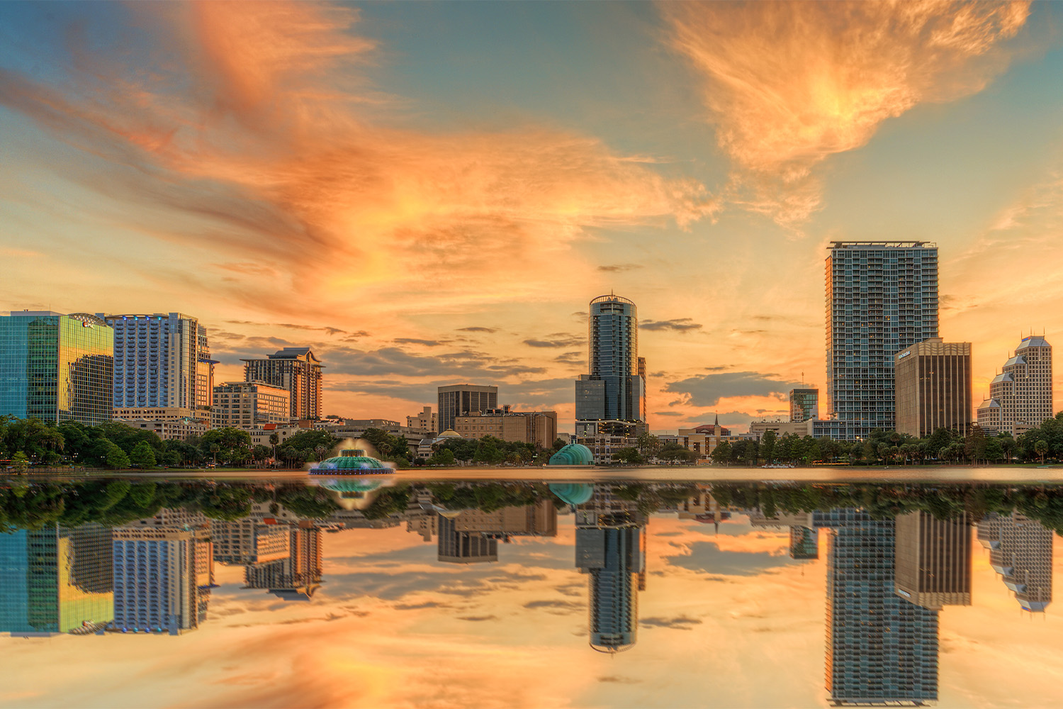 A colorful sunset over Lake Eola and Orlando, Florida with reflections captured off the lake.