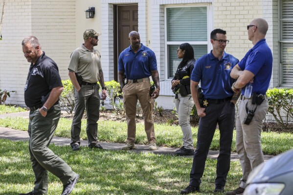 Detectives with the Hillsborough County Sheriff's Office join an investigation inside the Lake Forest subdivision of Tampa, Fla., on Friday, April 24, 2026, where authorities said a man was taken into custody after barricading himself inside a home, in connection to the search for two missing University of South Florida graduate students. (Douglas R. Clifford/Tampa Bay Times via AP)