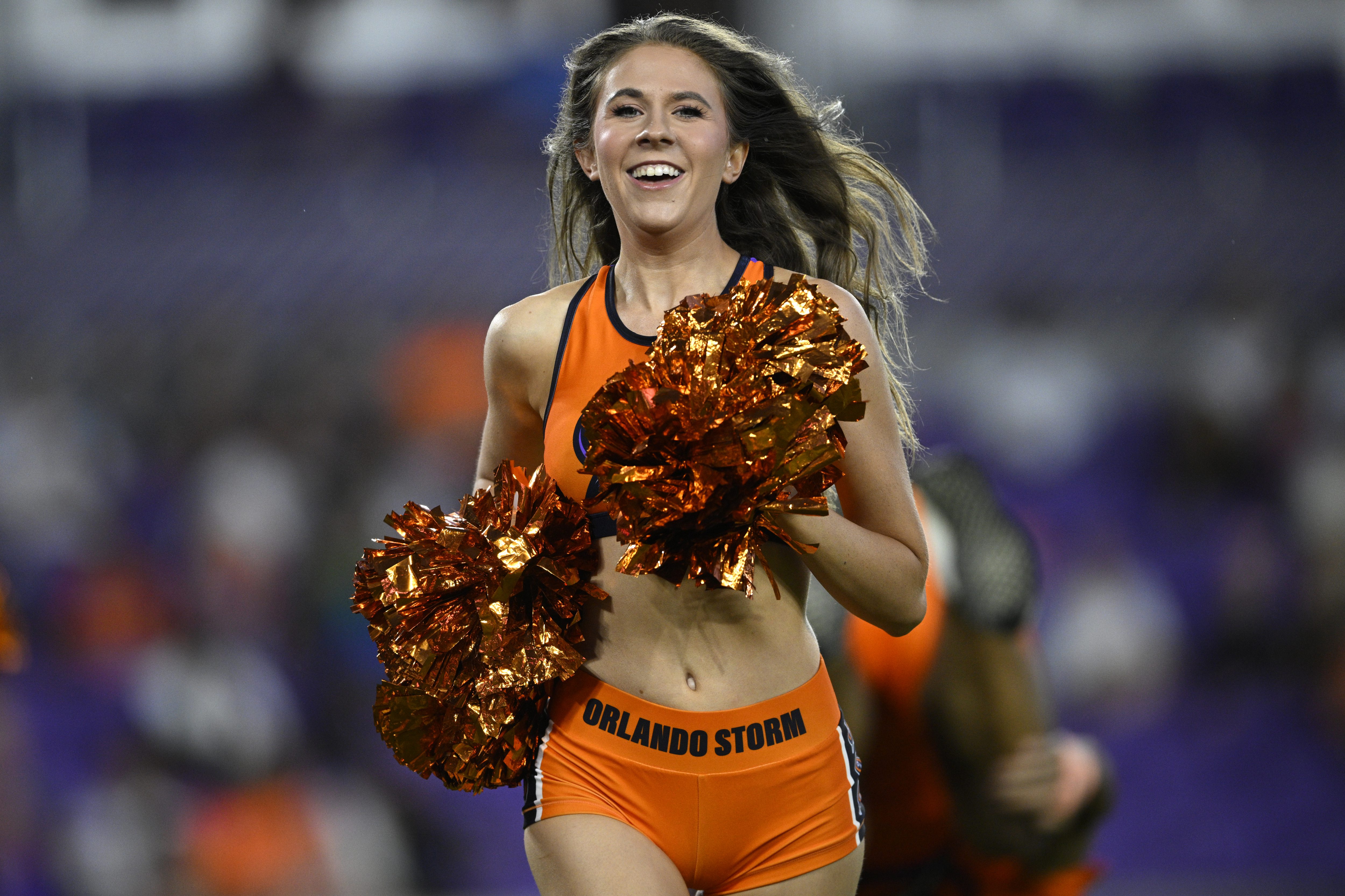 An Orlando Storm cheerleader runs off of the field after...