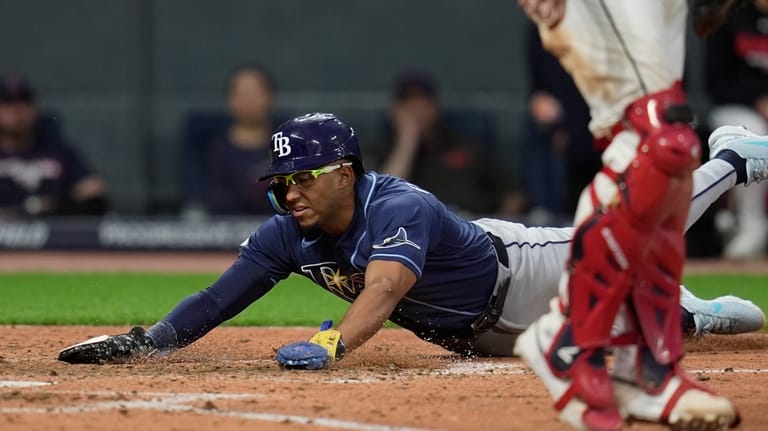 Tampa Bay Rays' Richie Palacios, left, scores behind Cleveland Guardians...
