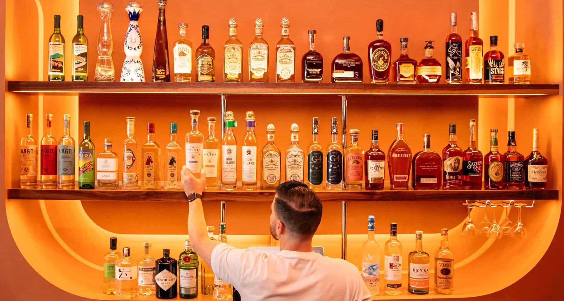 Bartender getting a drink in front of an orange bar