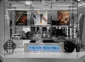 Tsar Bomba retail display with illuminated brand signage, watch showcases, and large posters featuring interchangeable watches, a skeleton model, and a lifestyle wrist shot inside a modern store environment.
