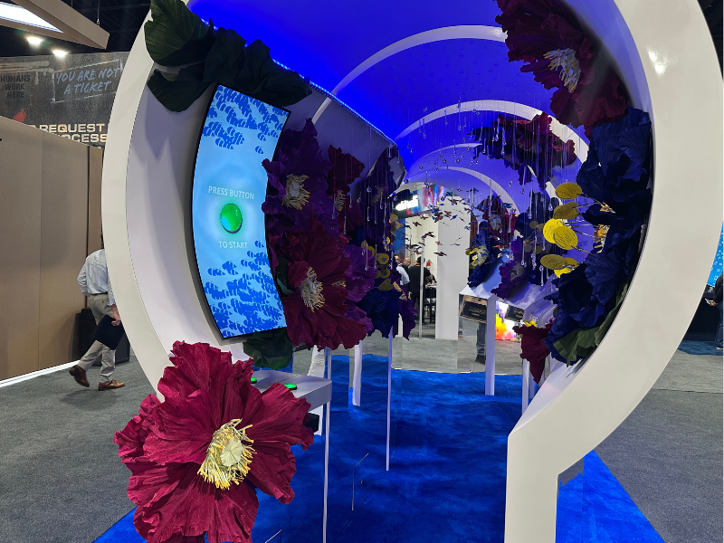 Walk-through tunnel exhibit that is lit up with LED lights, includes large flower sculptures and an interactive monitor.