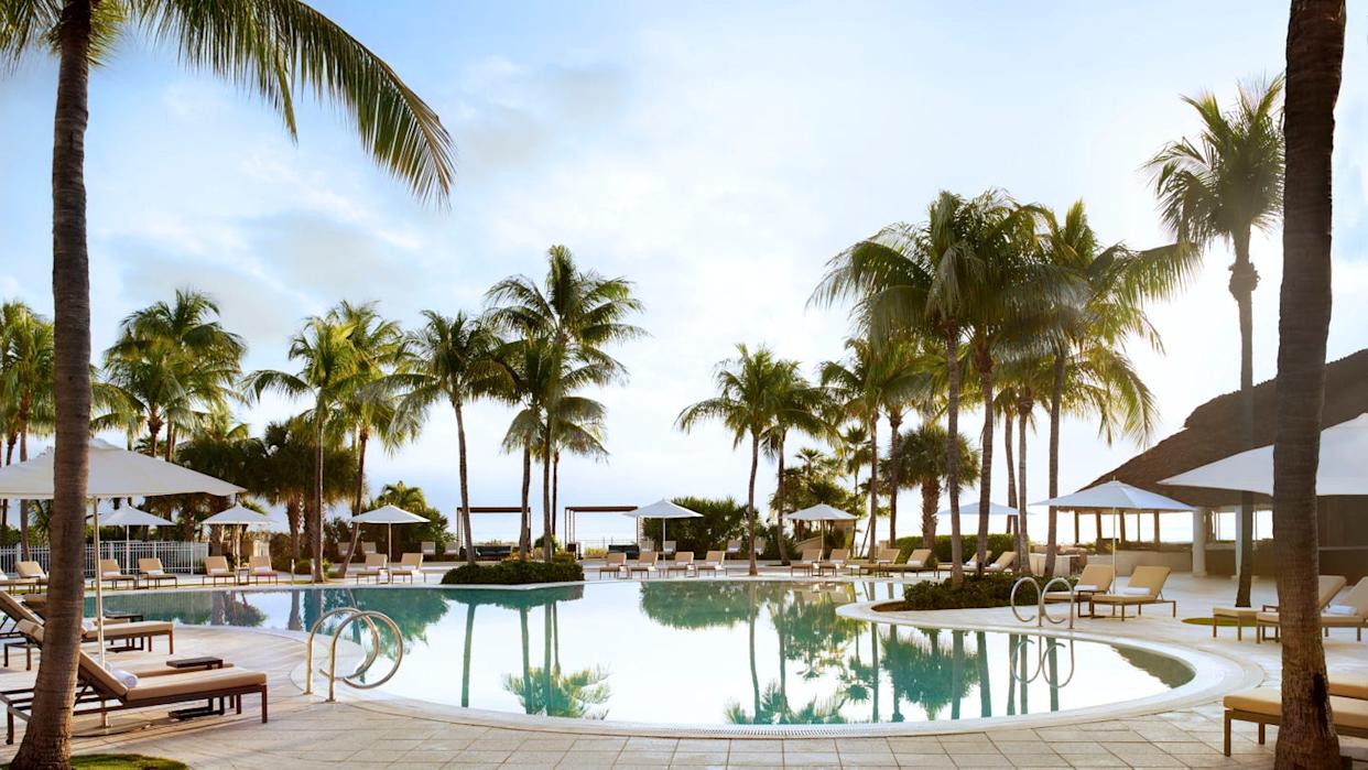 Luxurious outdoor swimming pool surrounded by palm trees and lounge chairs.