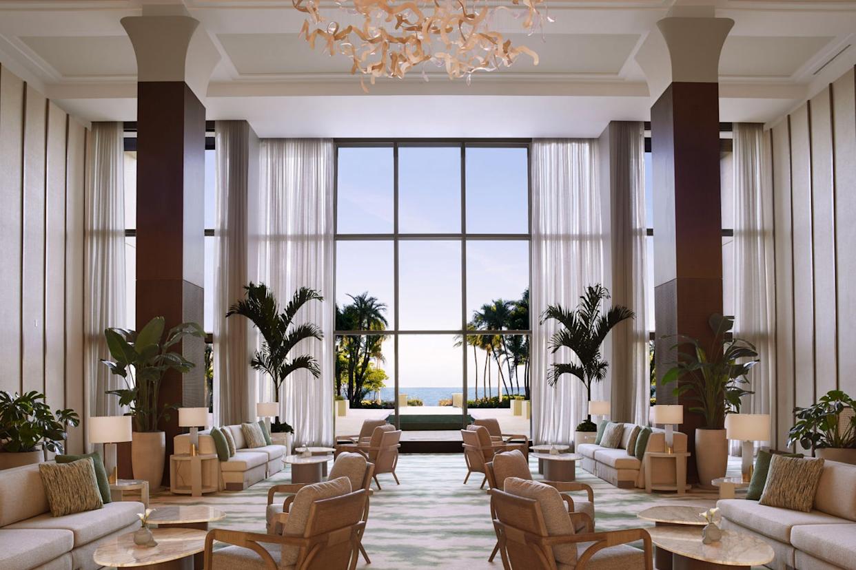 A spacious and elegantly designed hotel lobby with large windows and ocean view.