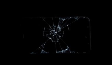 An extreme close-up of a shattered smartphone screen reflecting a distorted, harsh light, conceptually illustrating the aftermath of a digital scam.