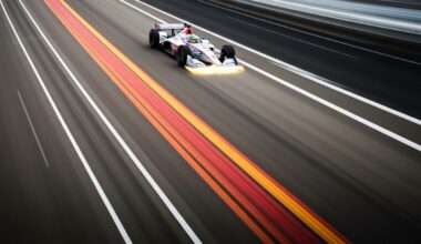 An abstract, blurred image of an INDYCAR vehicle in motion, with vibrant streaks of color representing the speed and energy of the sport.