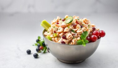 A high-end, photorealistic studio still-life photograph featuring a polished stainless steel bowl filled with various chicken salad ingredients like shredded chicken, celery, grapes, and herbs, arranged elegantly on a clean, monochromatic background, conceptually representing the premium quality and craftsmanship of Chicken Salad Chick
