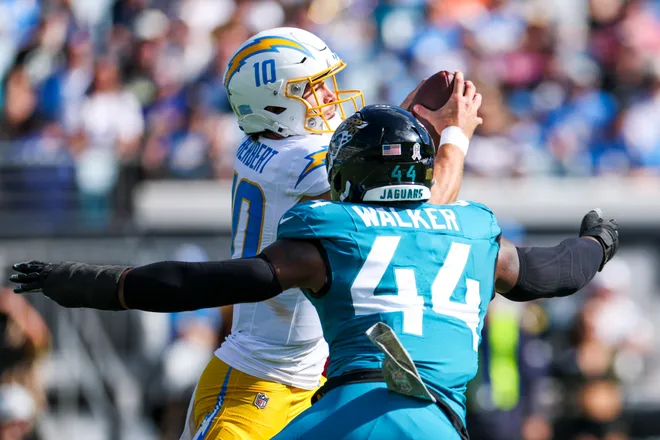 Nov 16, 2025; Jacksonville, Florida, USA; Los Angeles Chargers quarterback Justin Herbert (10) attempts to step away from pressure by Jacksonville Jaguars defensive end Travon Walker (44) during the first quarter at EverBank Stadium. Mandatory Credit: Nathan Ray Seebeck-Imagn Images