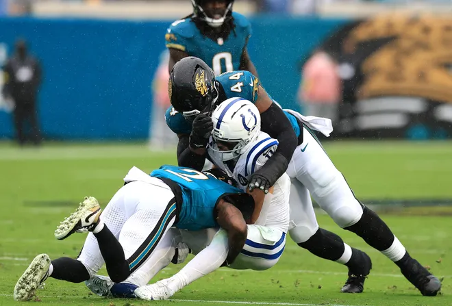 JACKSONVILLE, FLORIDA - DECEMBER 07: Jourdan Lewis #2 and Travon Walker #44 of the Jacksonville Jaguars tackle Michael Pittman Jr. #11 of the Indianapolis Colts during the second quarter at EverBank Stadium on December 07, 2025 in Jacksonville, Florida. (Photo by Mike Carlson/Getty Images)