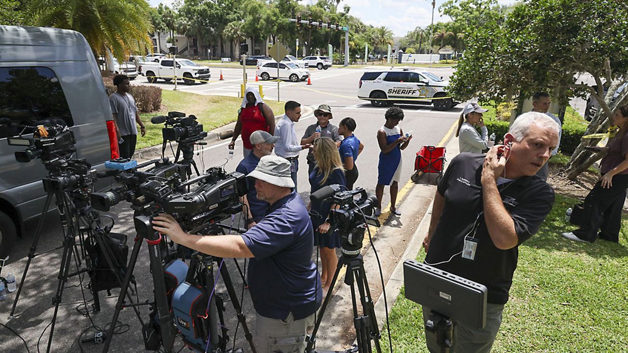 Members of the media document detectives and deputies with the Hillsborough County Sheriff's Office as they investigate inside the Lake Forest subdivision of Tampa, Fla., on Friday, April 24, 2026, where authorities said a man was taken into custody after barricading himself inside a home, in connection to the search for two missing University of South Florida graduate students. (Douglas R. Clifford/Tampa Bay Times via AP)