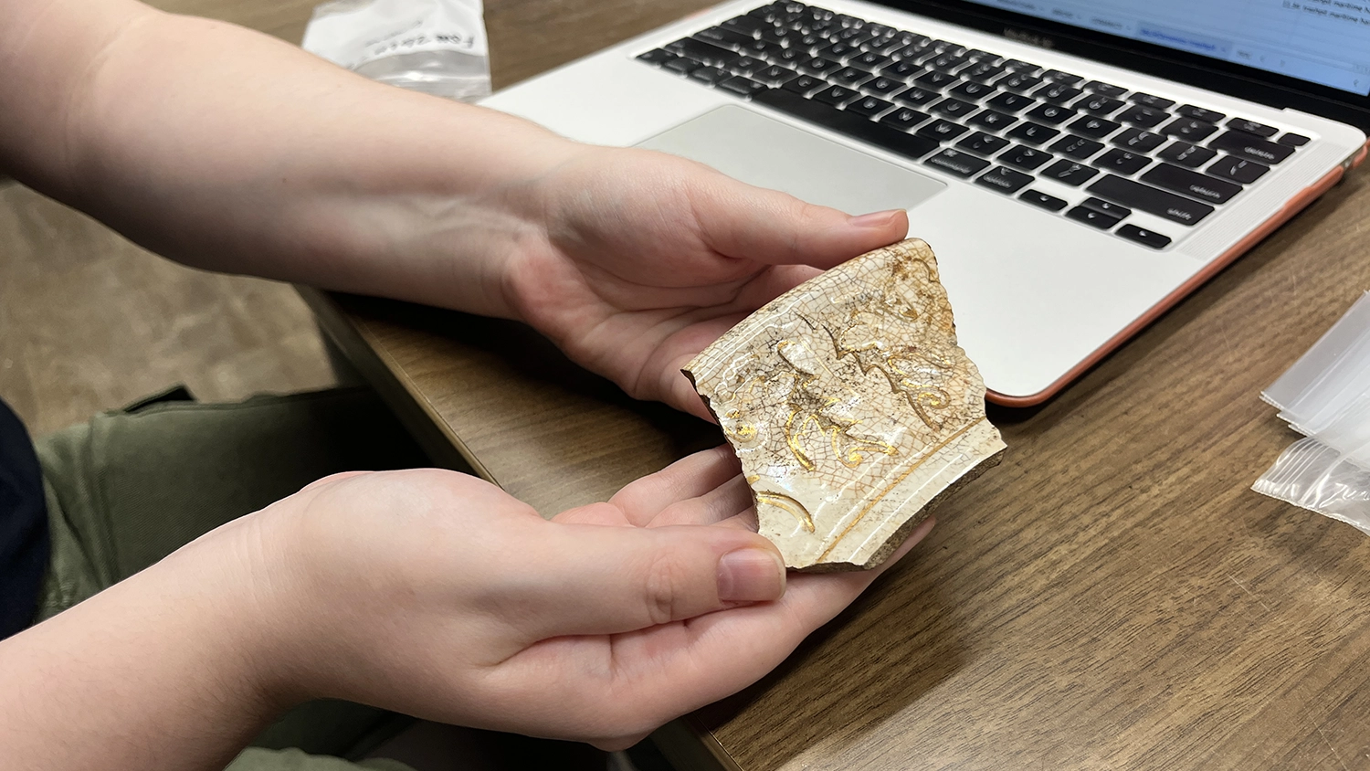 Flagler College archaeology student Abby Mahon shows off a shard from a piece of pottery that dates back to the 19th century.