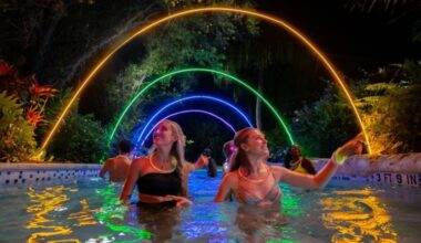 Two girls in the water under glowing lights at Aquatica Orlando for AquaGlow