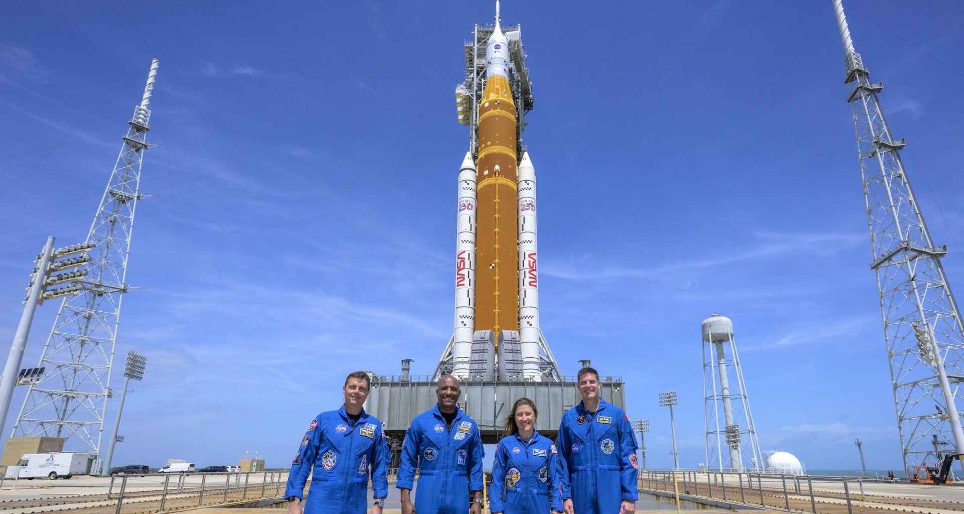 photo of the crew of Artemis II standing in front of its rocket in front of blue skies