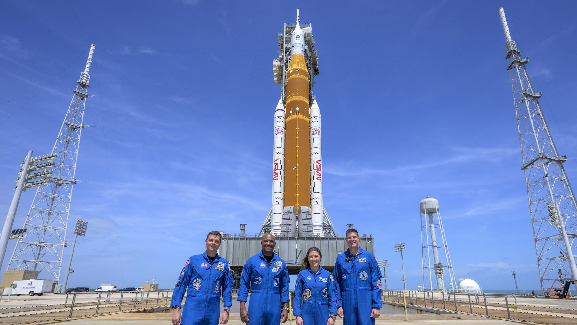 photo of the crew of Artemis II standing in front of its rocket in front of blue skies