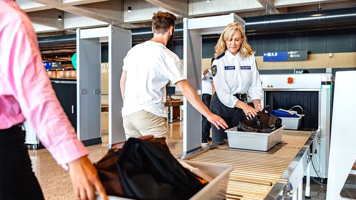Stock image of customs agents inspecting luggage at airport