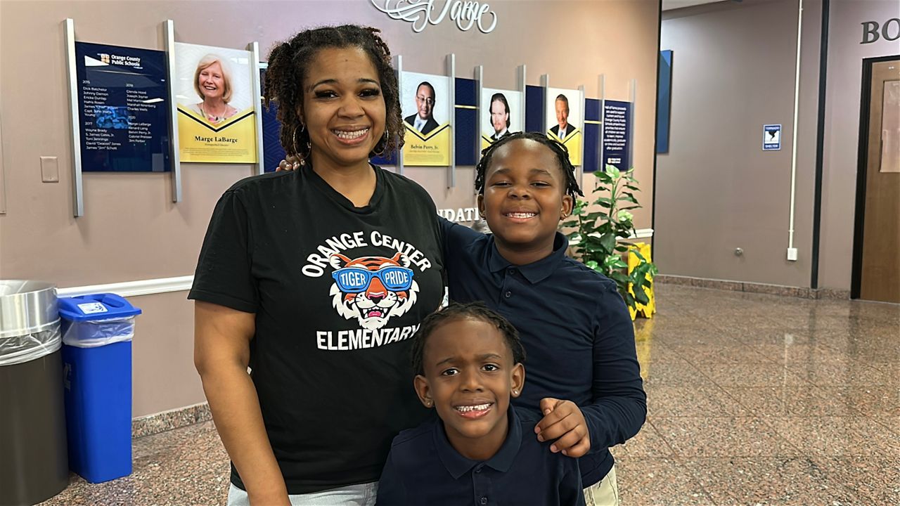 Dana Wallace and her sons Dallace and Dimitri are all smiles after Tuesday's OCPS vote to convert Orange Center Elementary. (Spectrum News)