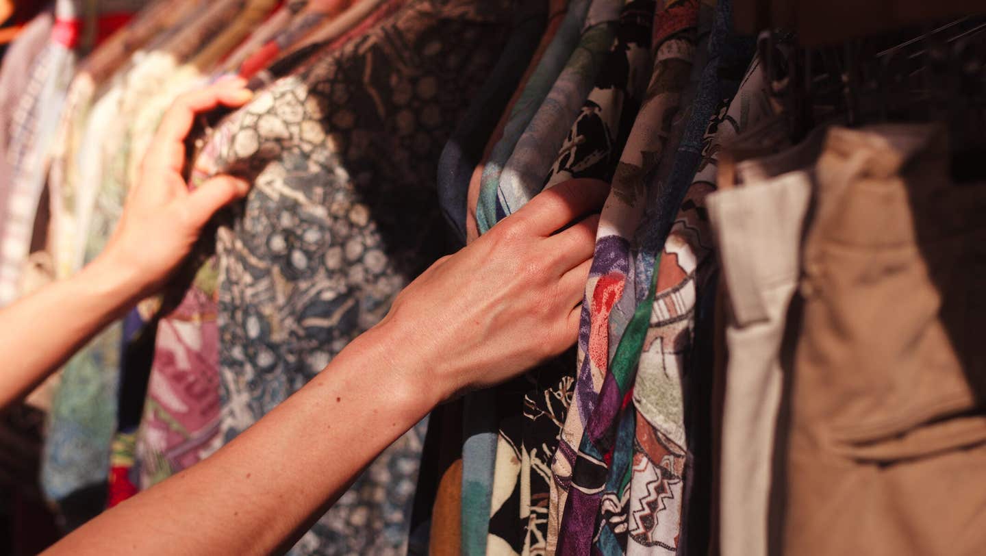 A young woman is browsing a rail of clothes at a street market