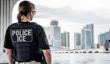 An ICE officer looks out over the Miami skyline.