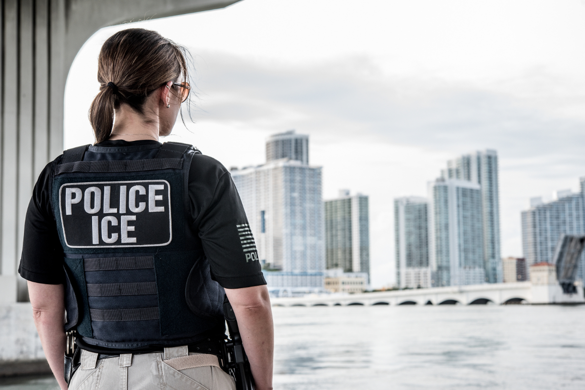 An ICE officer looks out over the Miami skyline.