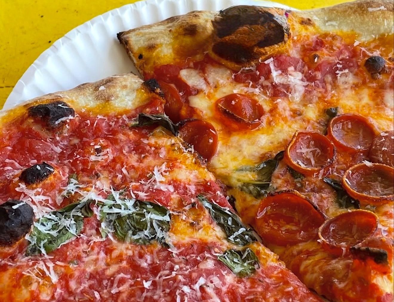 two slices of cheese pizza with pepperoni slices and shaved parm