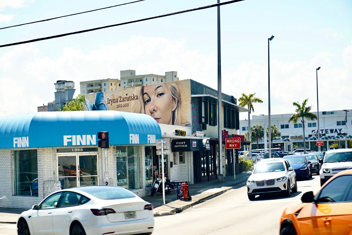 A photo of a street in Fort Lauderdale featuring a mural of a young blonde woman on the side of a building.