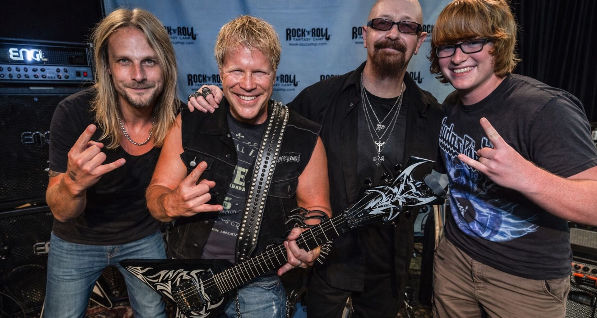 Photo of Judas Priest musicians posing with a fan at the Rock ’n’ Roll Fantasy Camp.