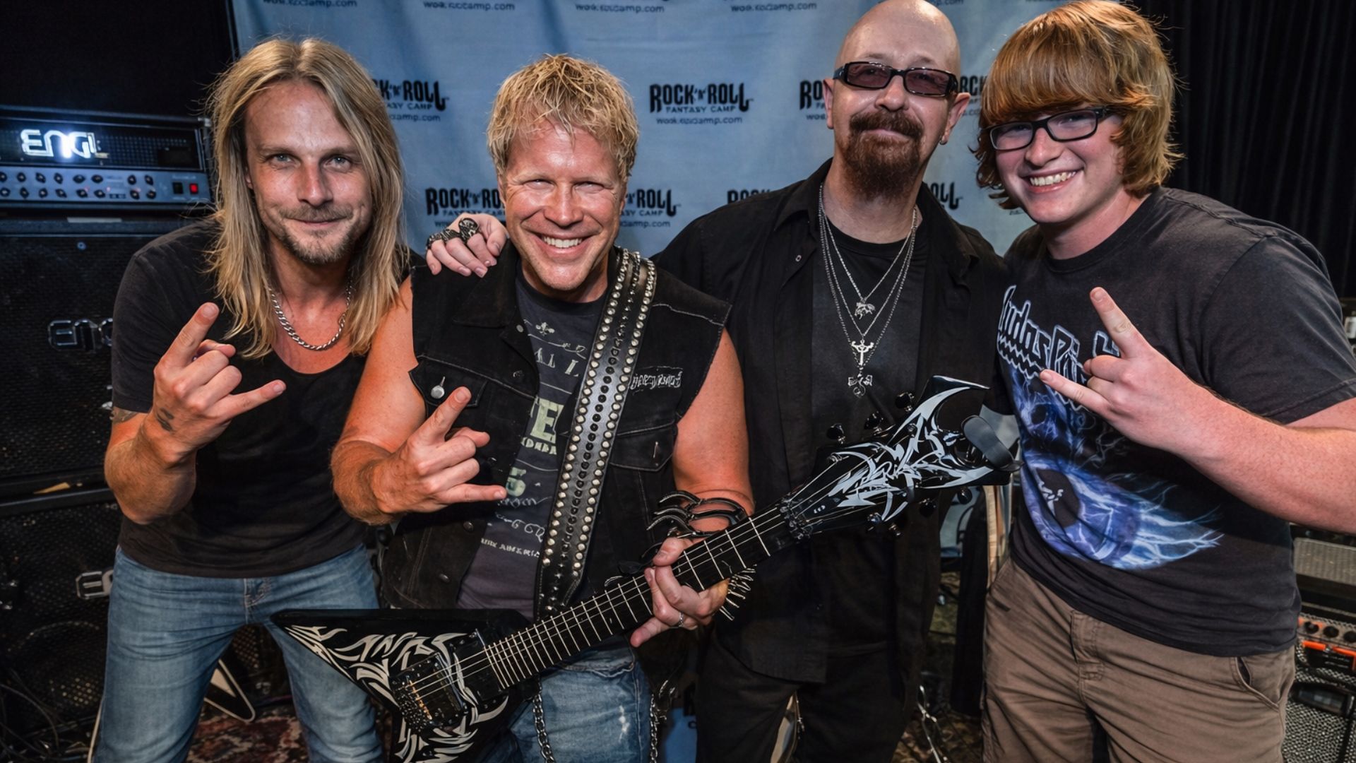 Photo of Judas Priest musicians posing with a fan at the Rock ’n’ Roll Fantasy Camp.