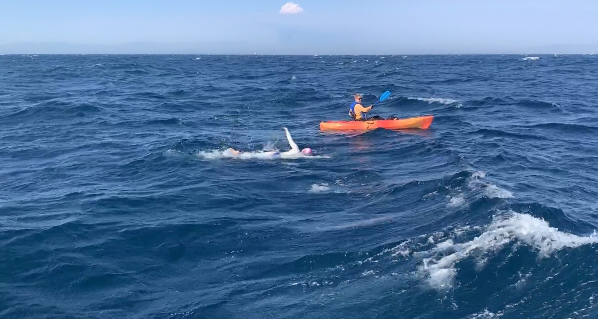 woman swimming next to kayak
