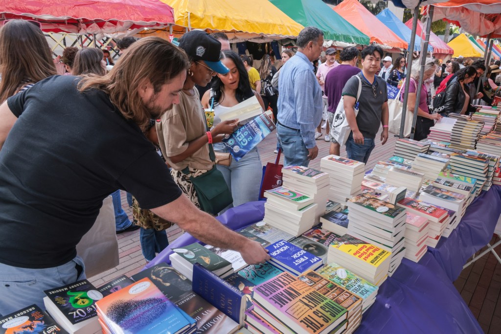 photo of people looking through books beneath tents at an outdoor book fair