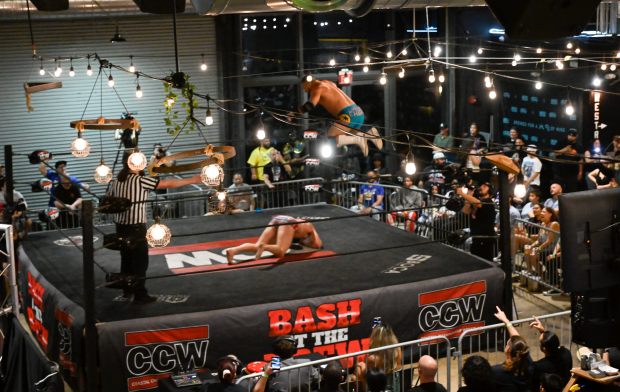Coastal Championship Wrestling wrestlers like Cha Cha Charlie, center, display feats of aerobatics at South Florida breweries, like the taproom of The Tank Brewing Co. in Doral. (Michele Eve Sandberg/Contributor)