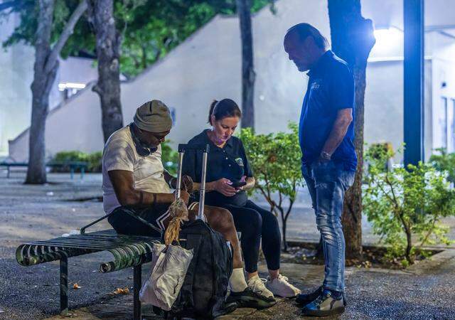 Ron Book, chair of the Miami-Dade County Homeless Trust, and Victoria Mallette, the Trust’s executive director, talk to a homeless man in downtown Miami as part of an overnight census on Aug. 21, 2025.