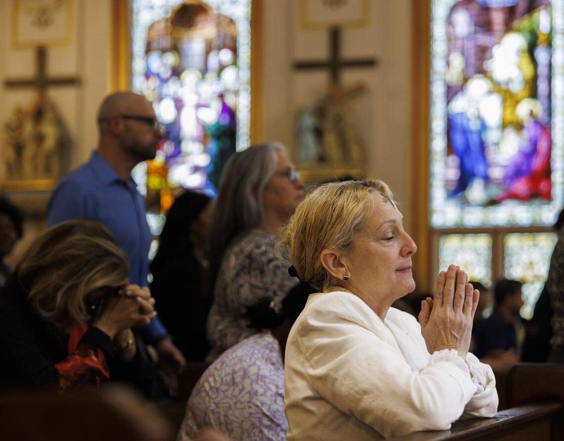 A woman prays after receiving ashes on her forehead during Ash Wednesday mass on Wednesday, Feb. 18, 2026, at Gesu Catholic Church in downtown Miami. The mass was fully packed with standing room only at the back of the church.
