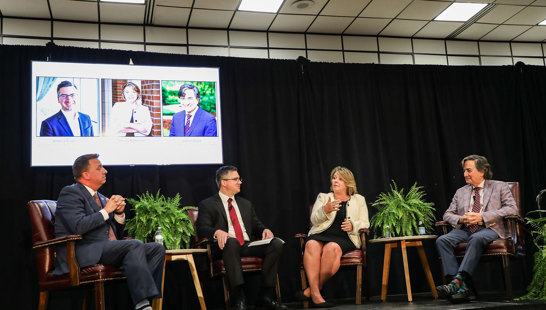 Four individuals sitting on a stage during a panel discussion.