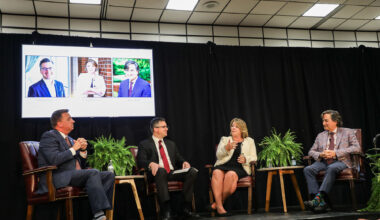 Four individuals sitting on a stage during a panel discussion.