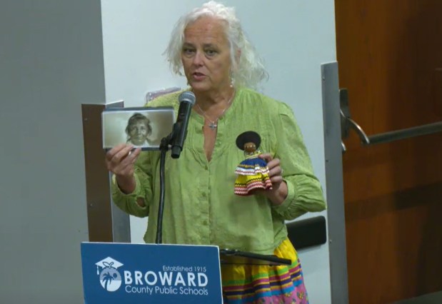 Sister Robin Haines Merrill, an artist and minister, speaks at a March 24 Broward School Board Workshop. She is holding a photo of Annie Jumper Tommie, a Seminole matriarch who ran a camp. Merrill said the school district needs to work with the Seminole Tribe of Florida related to the future use of the school, which will soon be closed. (BECON / Screen grab)