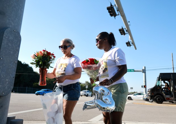 Megan Wilson, 43, left, and her sister Ebony Seay, 36, place flowers and balloons at the intersection where their father, Ronald Wilson, was killed in a February 16 pursuit by a BSO deputy in Tamarac. (Carline Jean/South Florida Sun Sentinel)