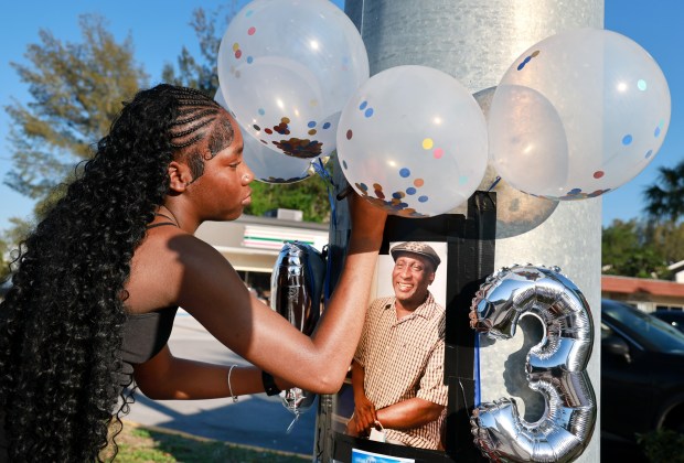 Nylah Simon, 14, places balloons at a makeshift memorial for her grandfather, Ronald Wilson, on Monday, March 23, 2026, a month after Wilson died during a crash that occurred as a Broward Sheriff's Office deputy pursued a fleeing driver. (Carline Jean/South Florida Sun Sentinel)