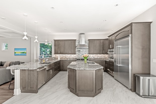 Viking appliances, dual farmhouse sinks, a pot filler, and a generous center island create a chef-driven layout without sacrificing style. (Photo courtesy of Pozek Group)