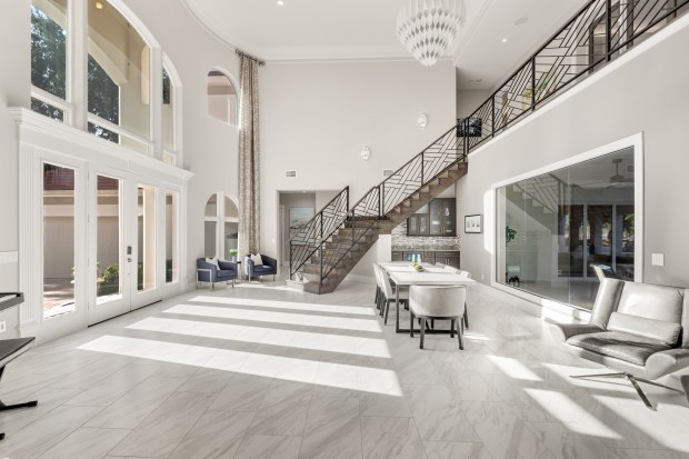 The front entrance leads right into the great room, which has soaring ceilings and a view of the lanai. (Photo courtesy of Pozek Group)
