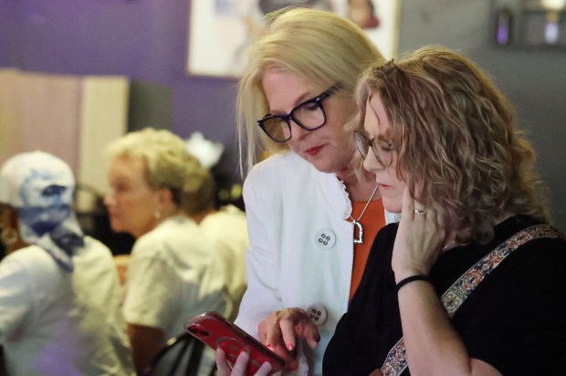 Apopka mayoral candidate Christine Moore (white jacket) looks over results with supporters at Just Like Momma's Soul Food & Wings in Apopka on Tuesday, April 14, 21026. (Stephen M. Dowell/Orlando Sentinel)