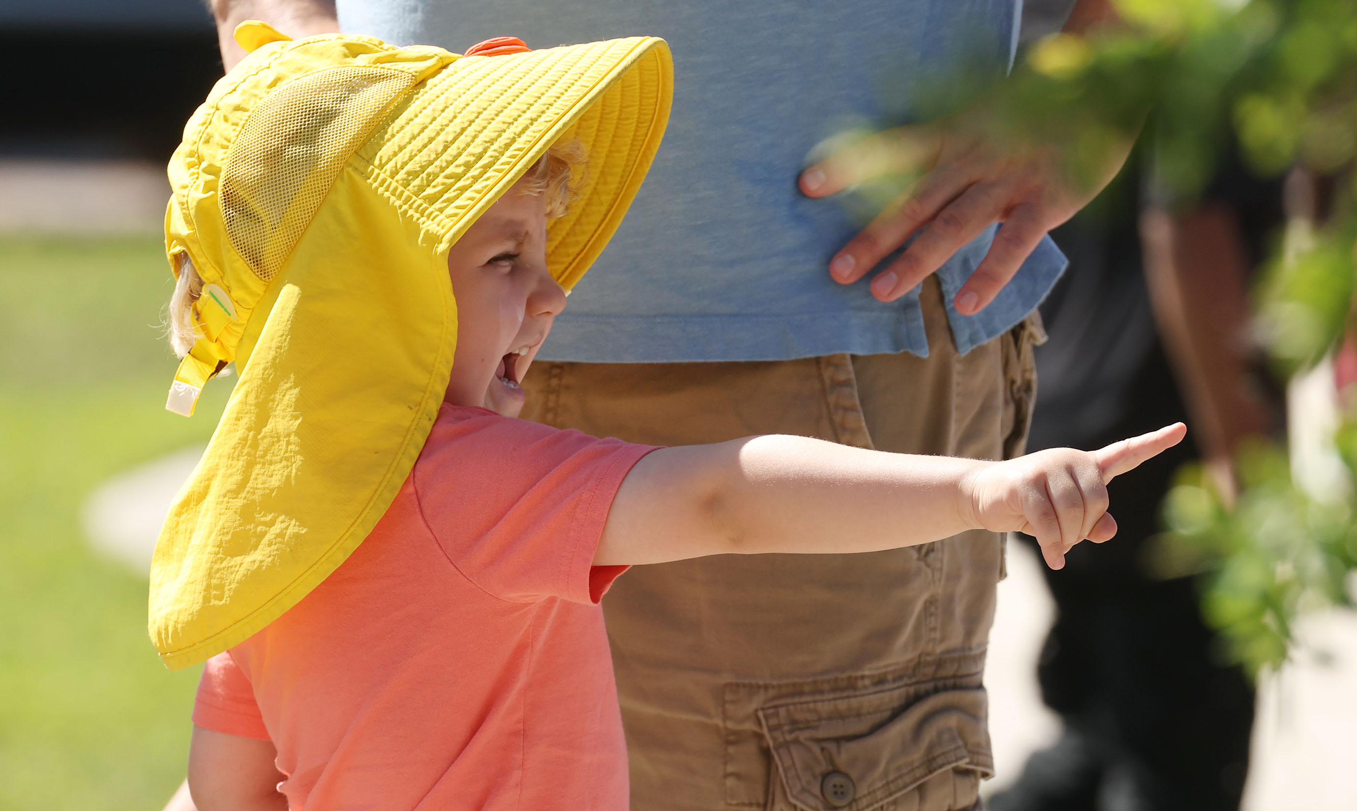 Wearing a colorful Easter hat, a child points during the...