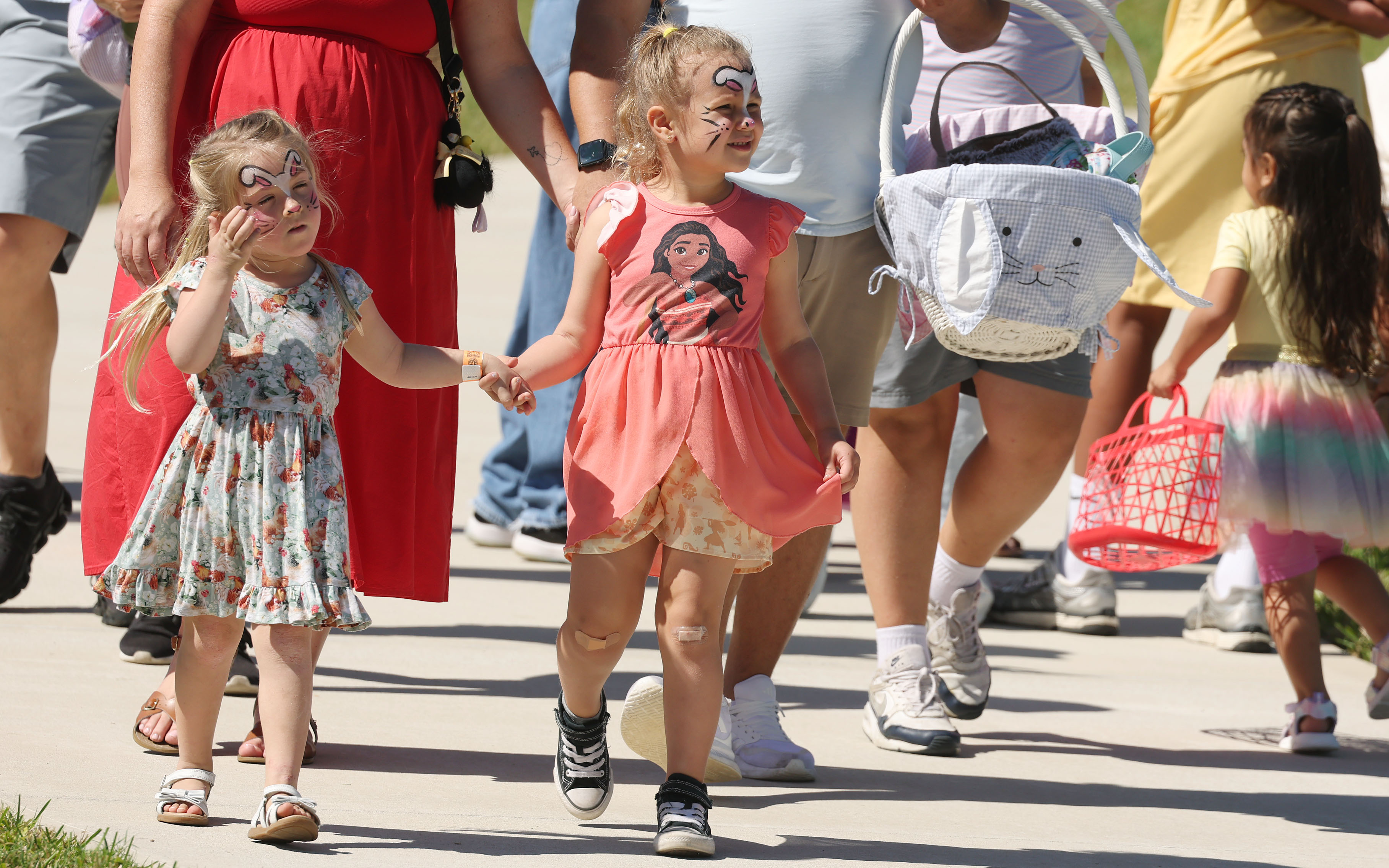 Face-painted girls hold hands during the Easter Eggstravaganza at the...