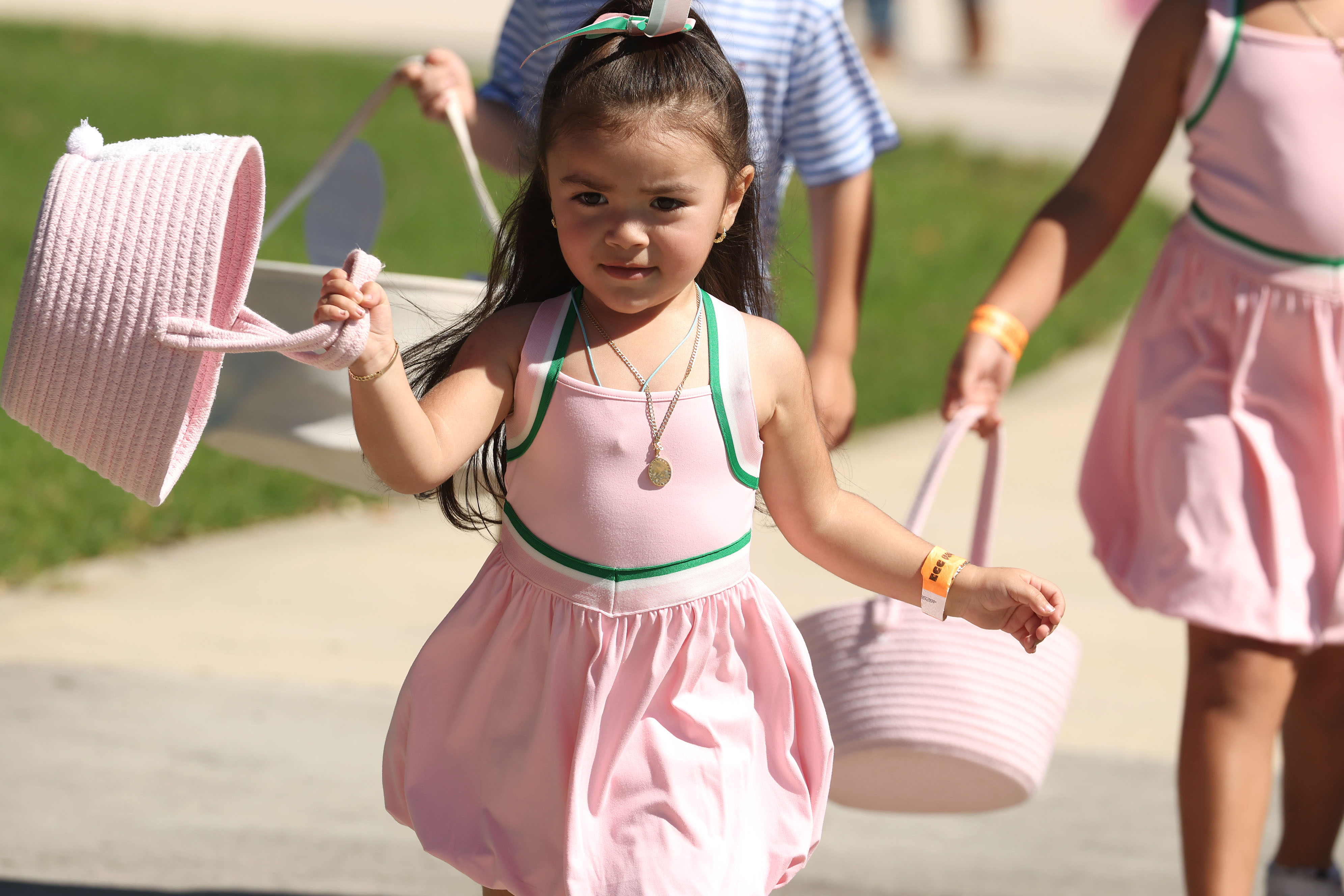 Dressed in her Easter finest, a girl swings her basket...