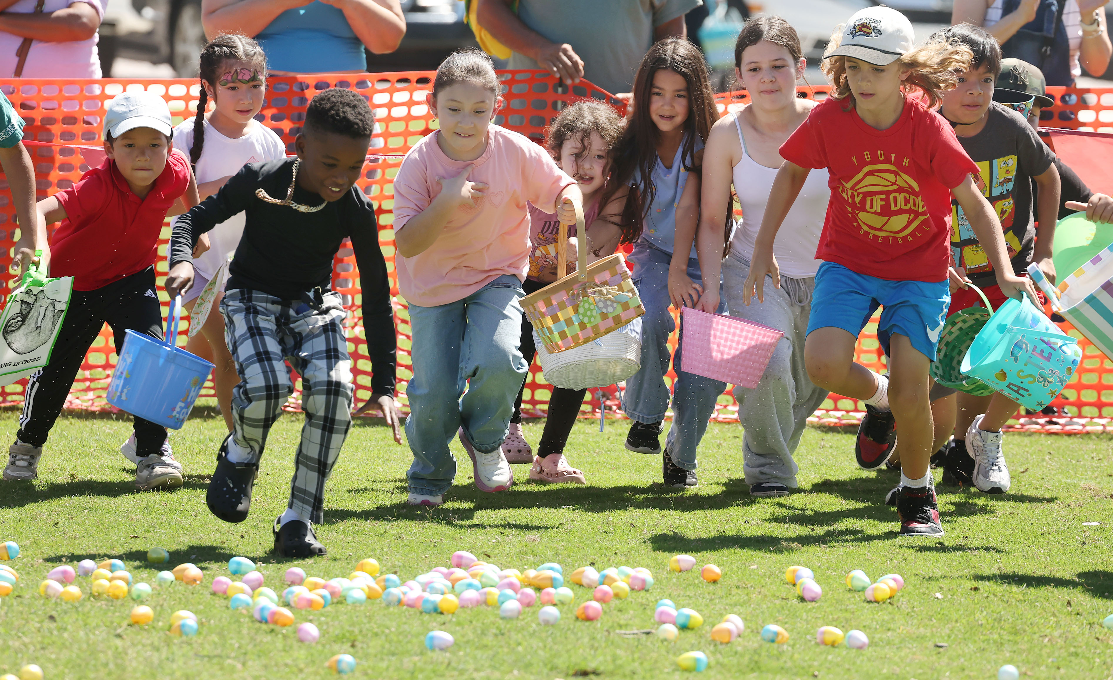 Children scurry to grab Easter eggs and candies from the...