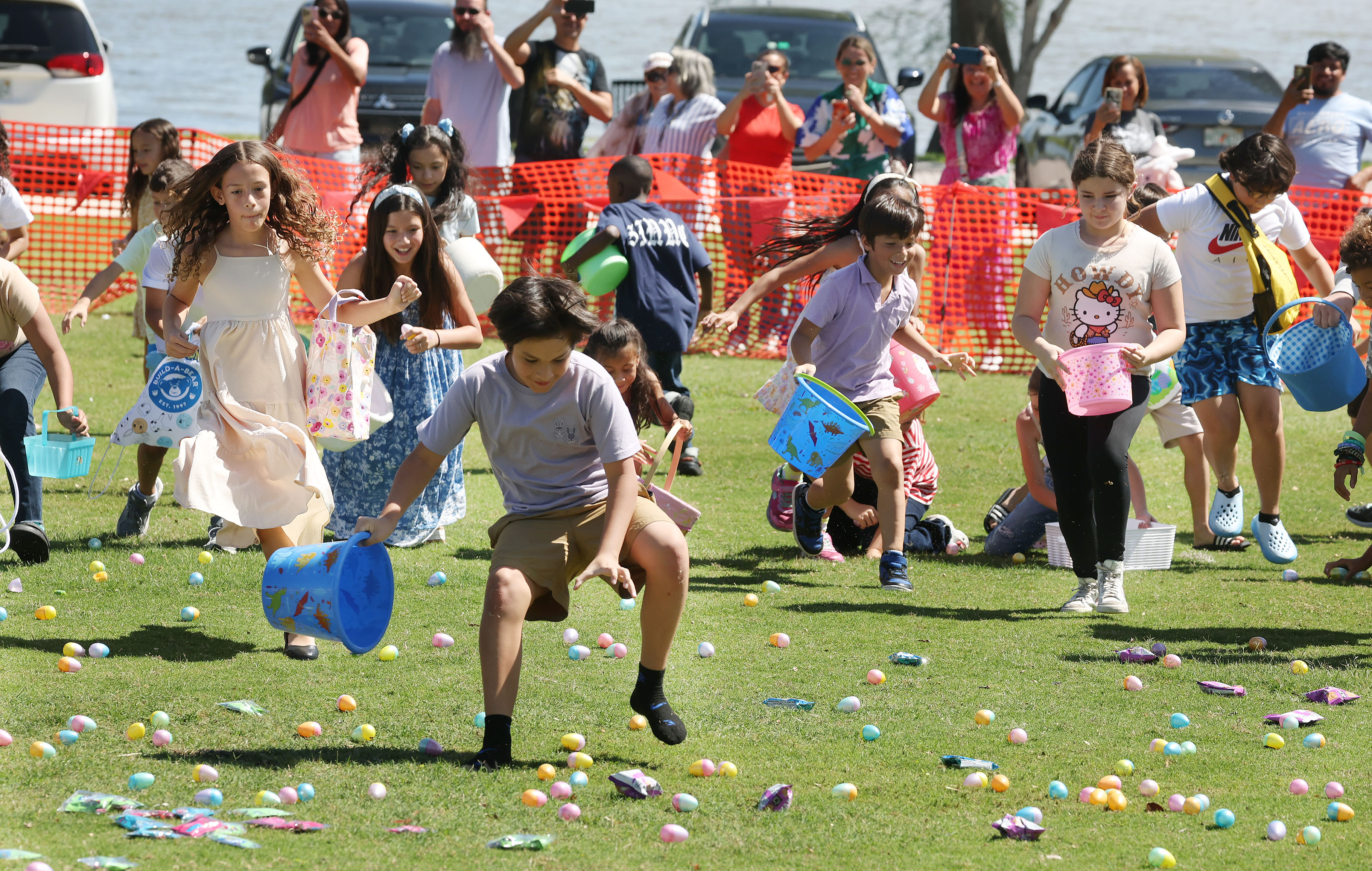 Children scurry to grab Easter eggs and candies from the...