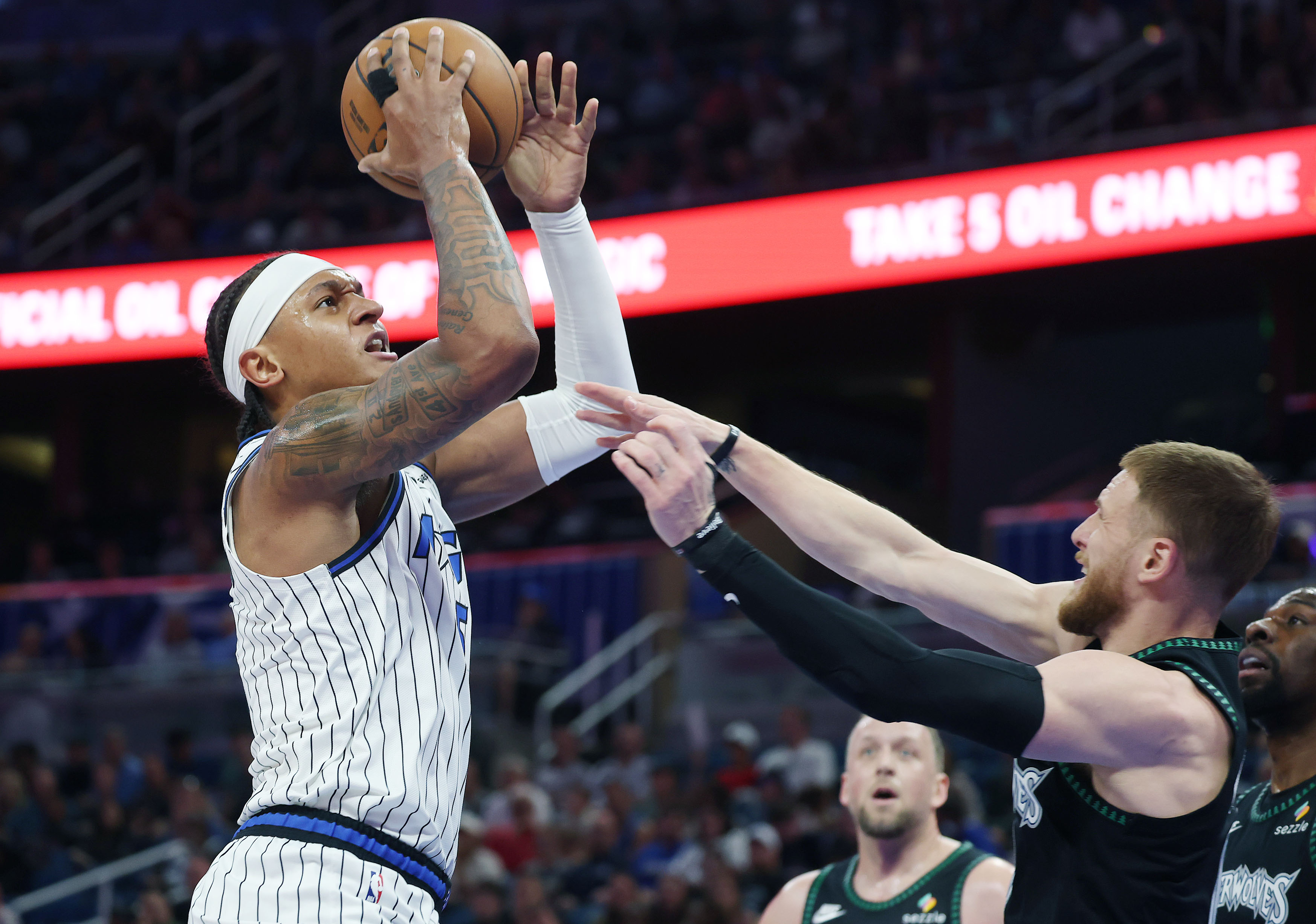 Orlando forward Paolo Banchero (left) scores over Minnesota guard Donte...