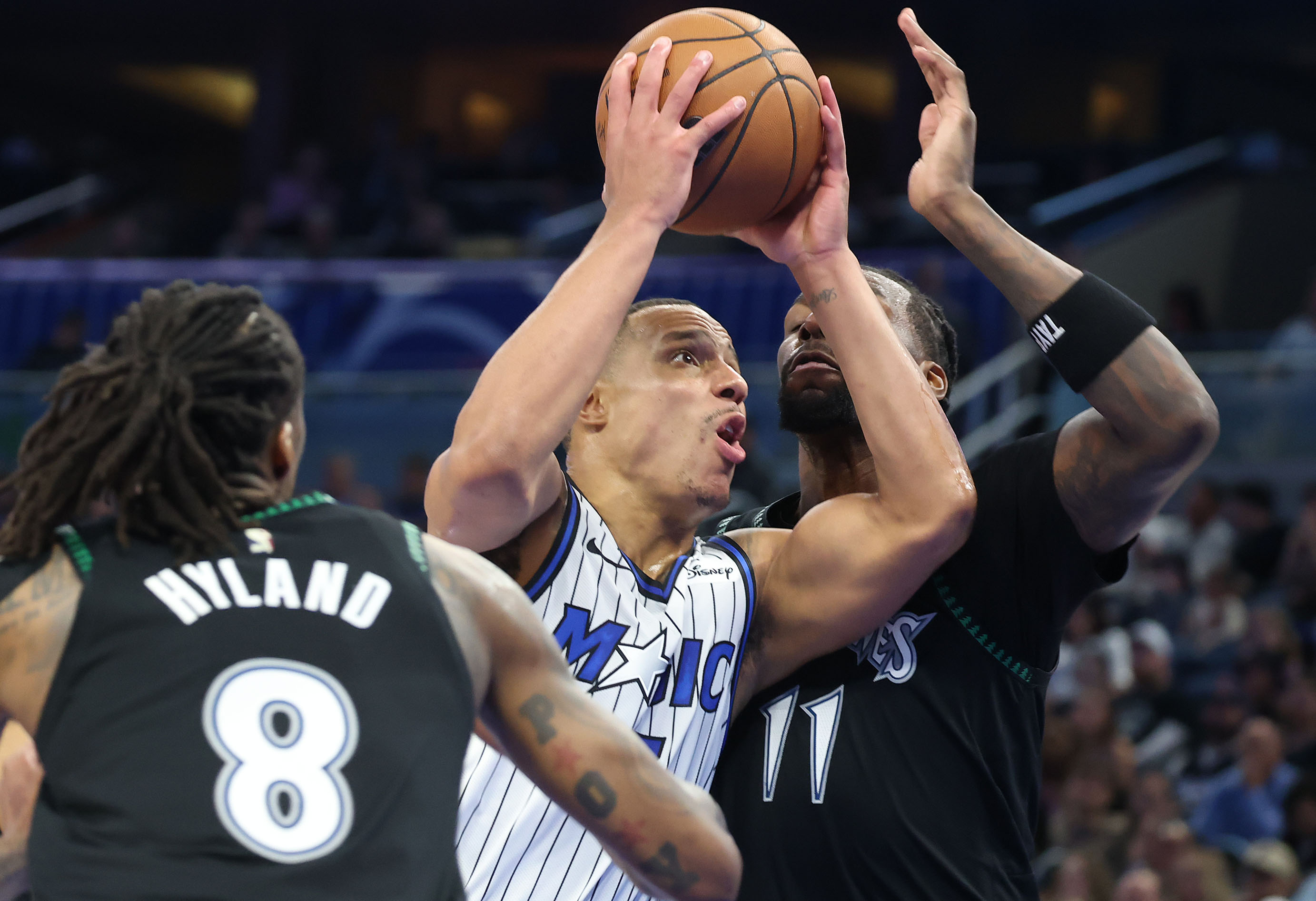 Orlando guard Desmond Bane (middle) drives through Minnesota center Naz...
