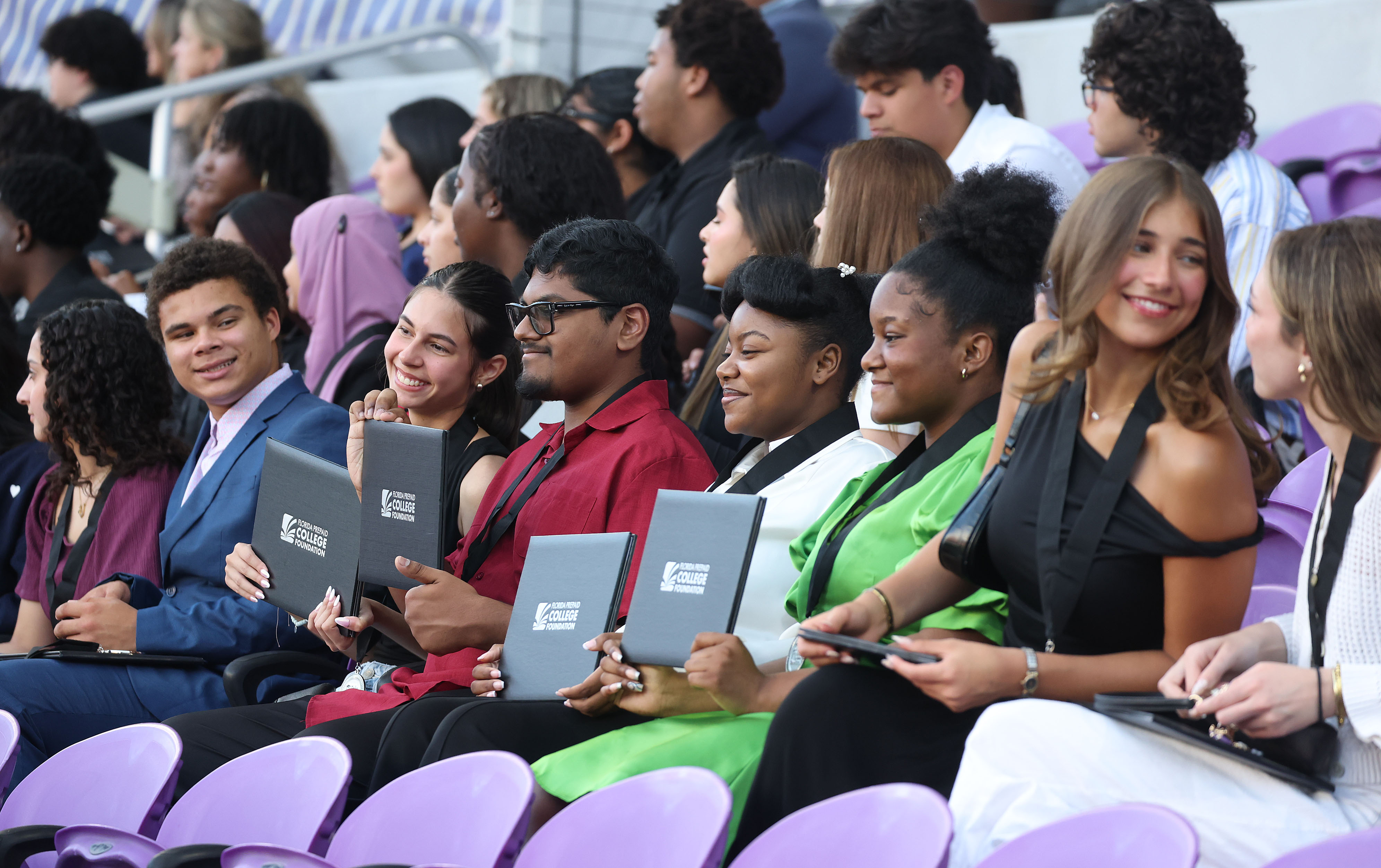 Graduates pose for photos while holding their diplomas during the...