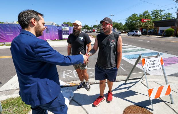 Austin Trahan and James Houchins, right, who were arrested Nov. 23 and charged with defacing the crosswalk at the Pulse nightclub memorial site with chalk, greet their attorney, Joshua Sinclair, left, outside the former club, Friday, April 24, 2026. Orange-Osceola State Attorney Monique Worrell announced Friday that she will not pursue charges in the case. (Joe Burbank/Orlando Sentinel)